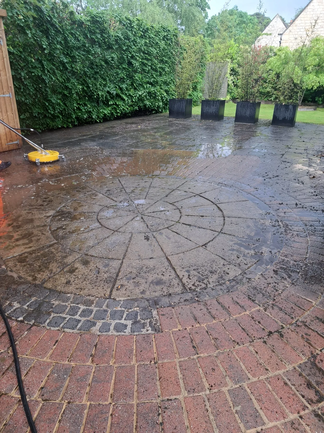 Pressure washing patio paving in progress with surface dirt being removed